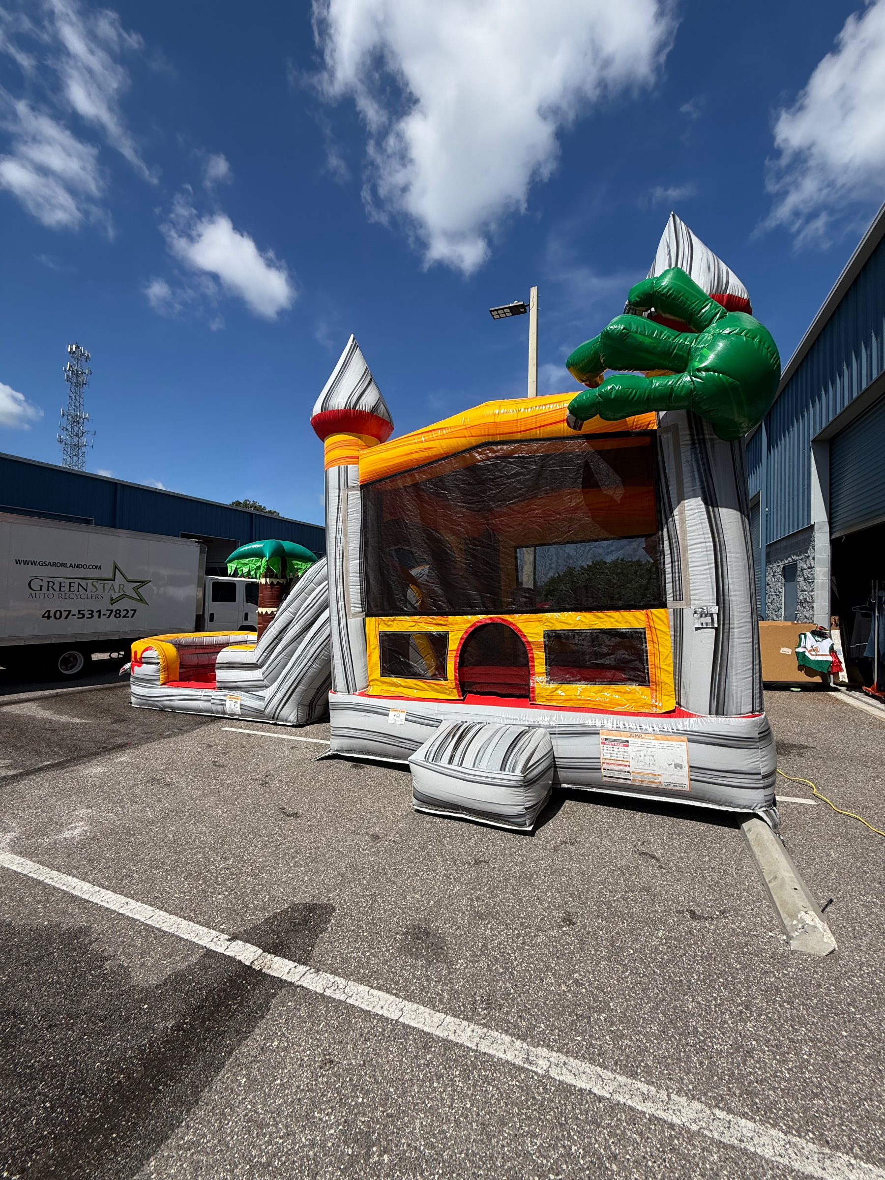 Dino bounce house front with mesh windows, gray towers and dinosaur roof decoration