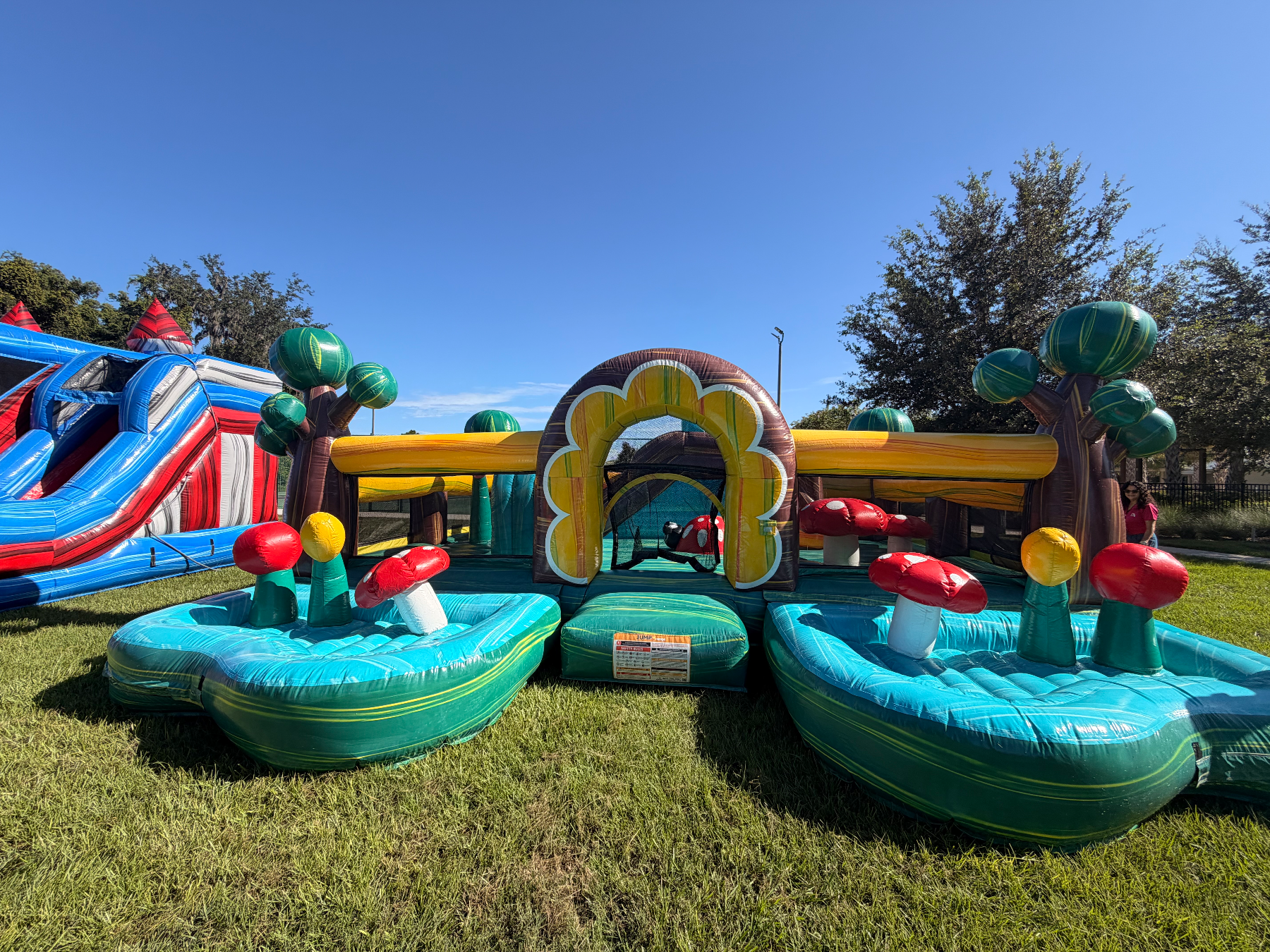 Front of toddler inflatable with twin turquoise play bays and mushroom obstacles