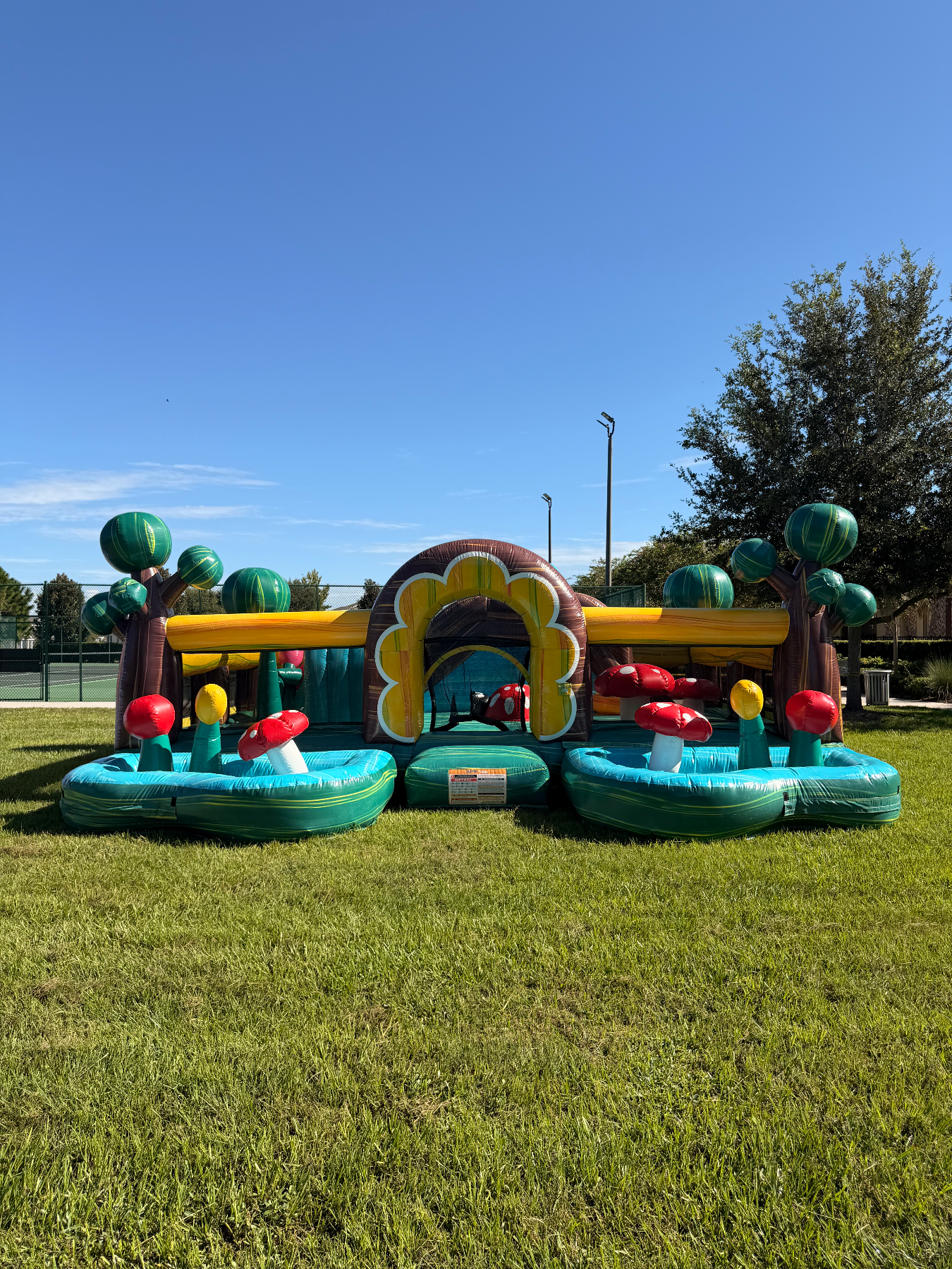 Toddler inflatable with turquoise play bays, red mushroom obstacles and jungle entrance arch