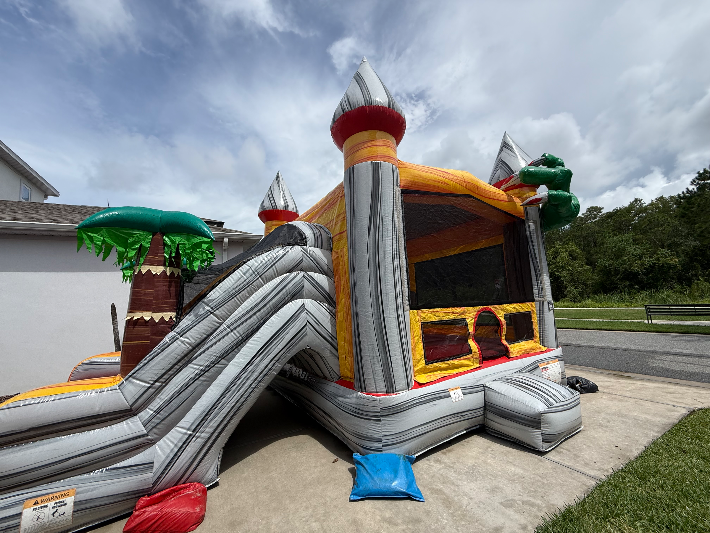 Rear-side view of Dino's gray towers and enclosed bounce area beside the slide