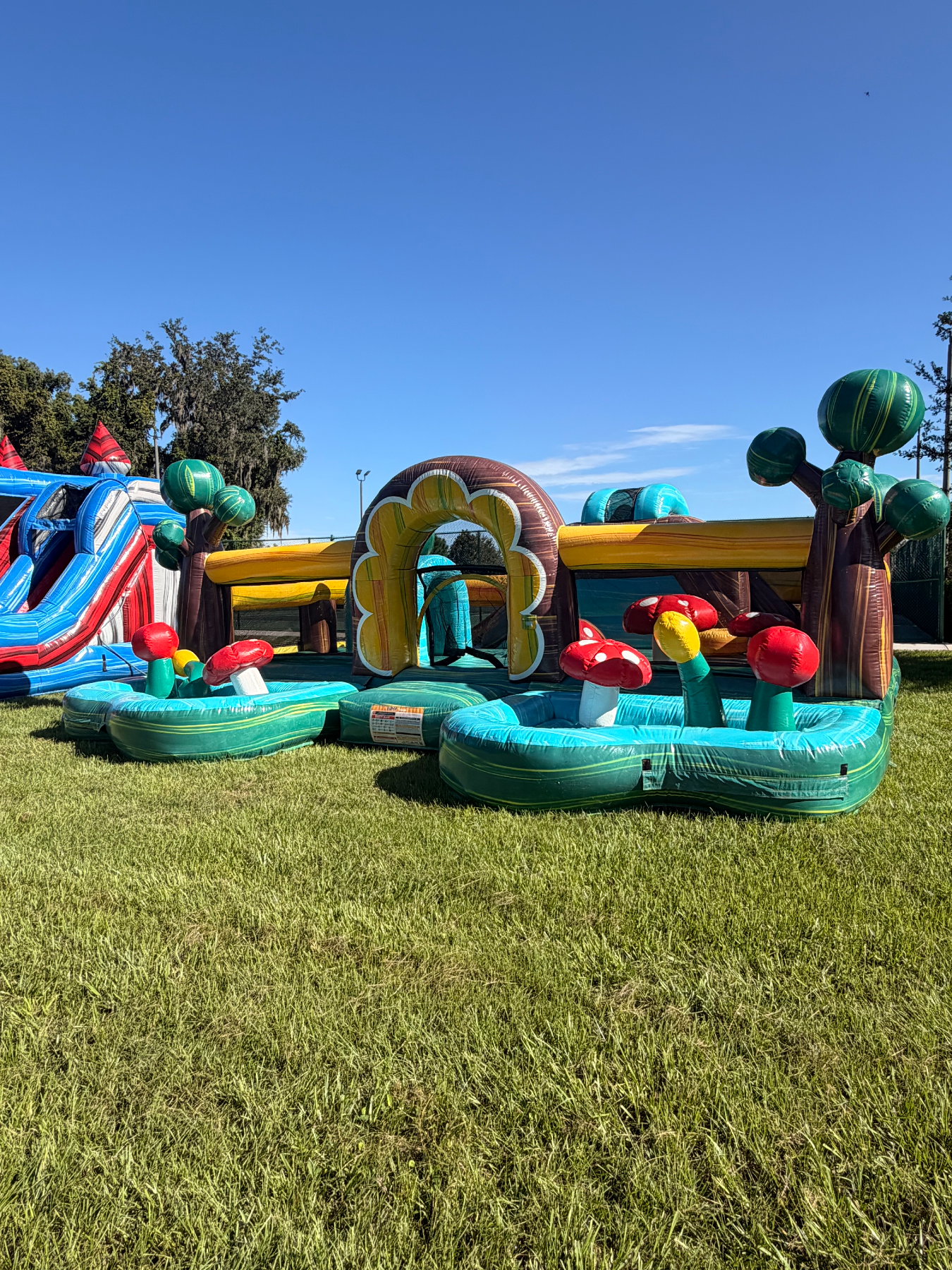 Toddler soft-play area beside a separate red and blue slide on grass