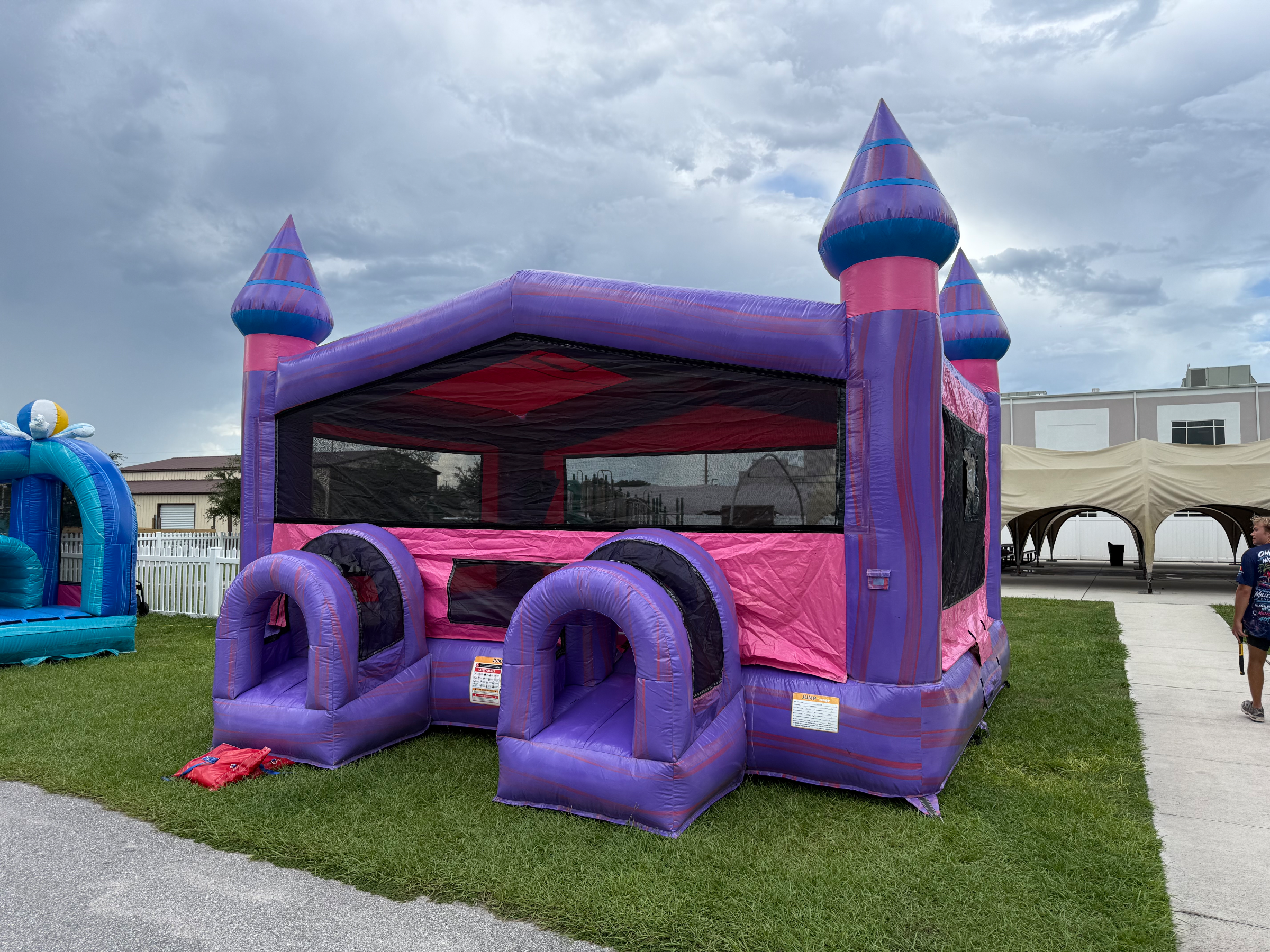 Mia XL Purple Palace with pink trim, pointed towers and two rounded entry tunnels on grass